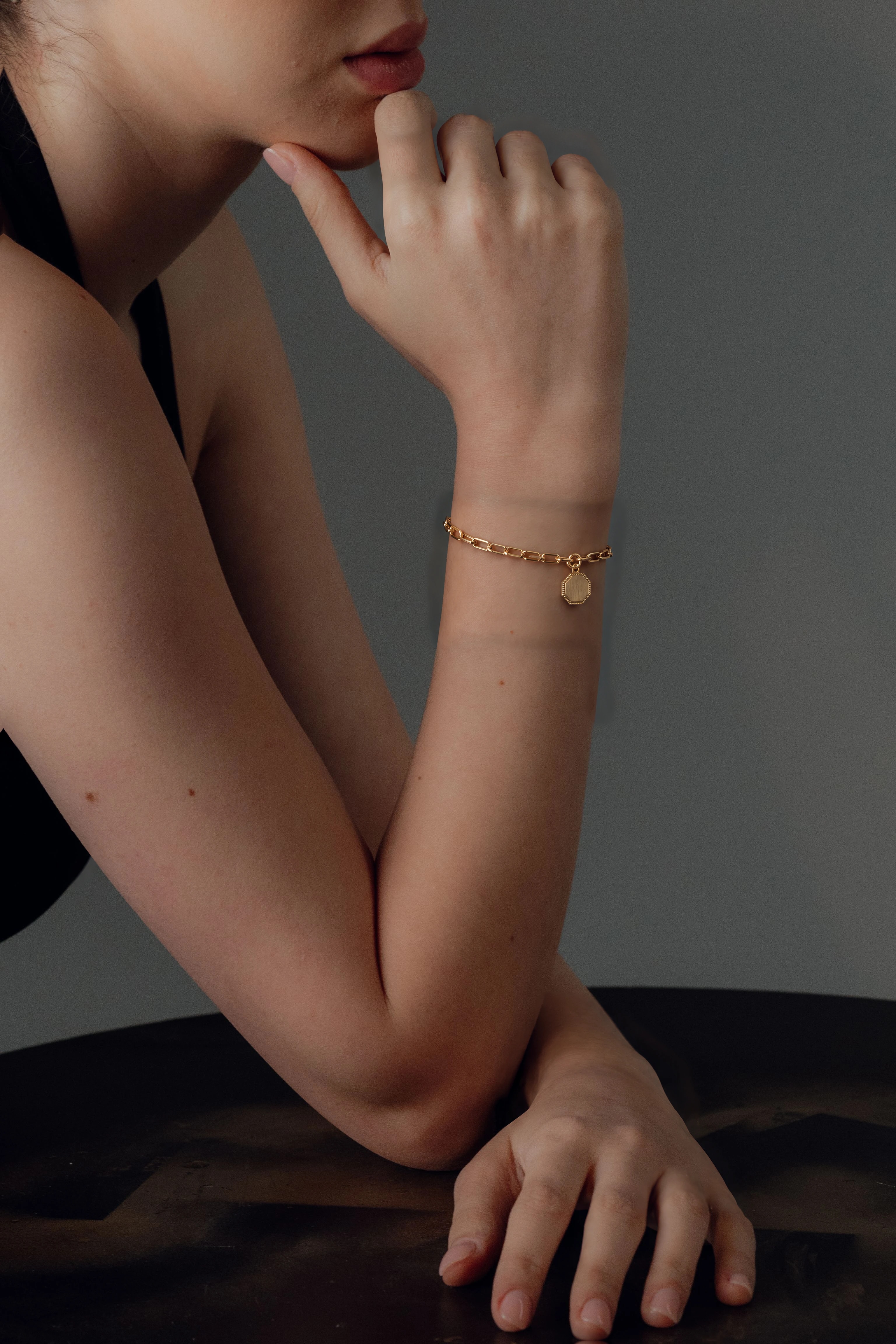 An arm resting on a table, wearing the VÉRA Fil Chain Bracelet