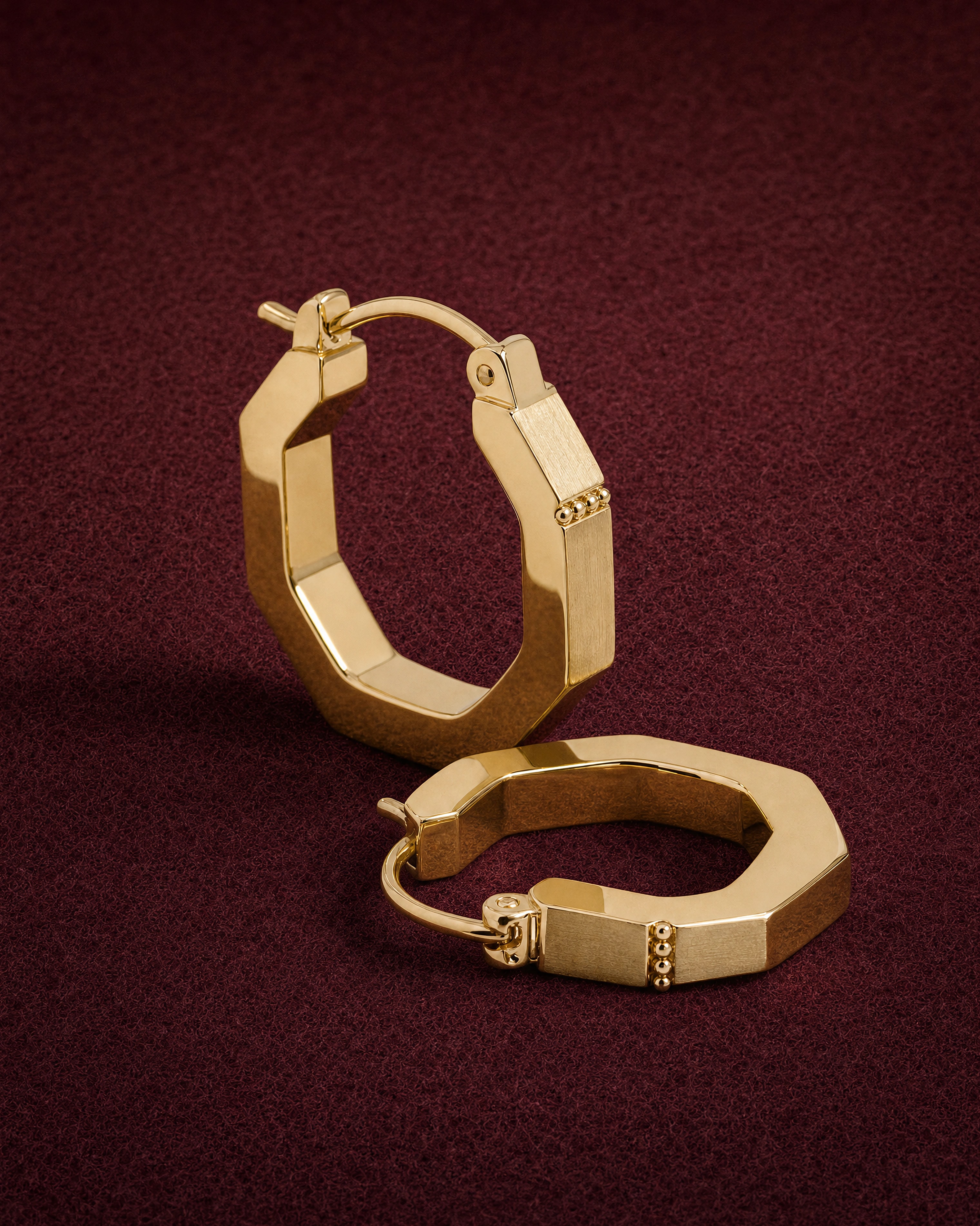 A pair of octagonal Arc Hoops in 14k yellow gold with a granule line by the hinge, on garnet jeweler's felt