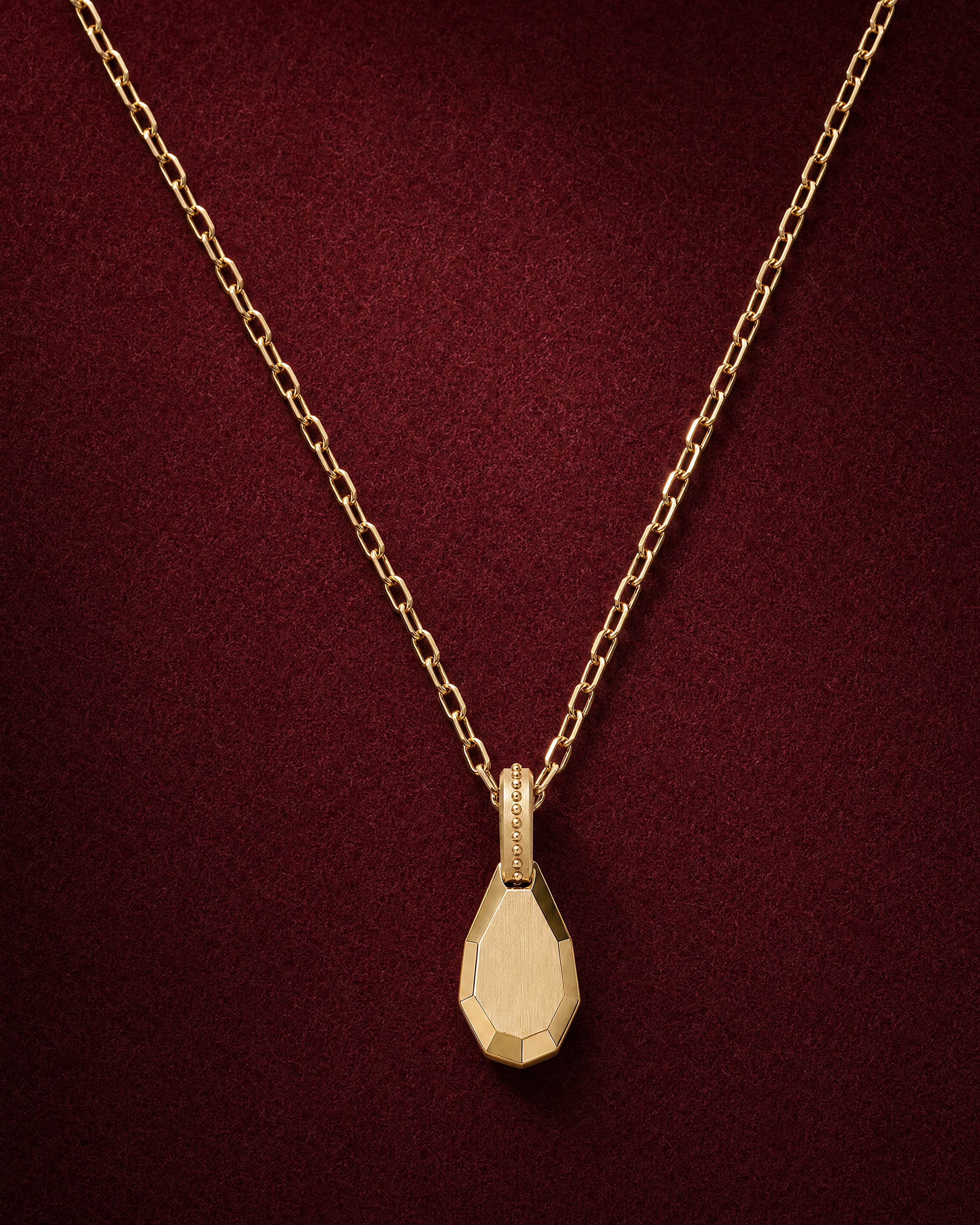 Drop Pendant: a faceted 18k gold teardrop on a fine octagonal-link chain, on garnet jeweler's felt