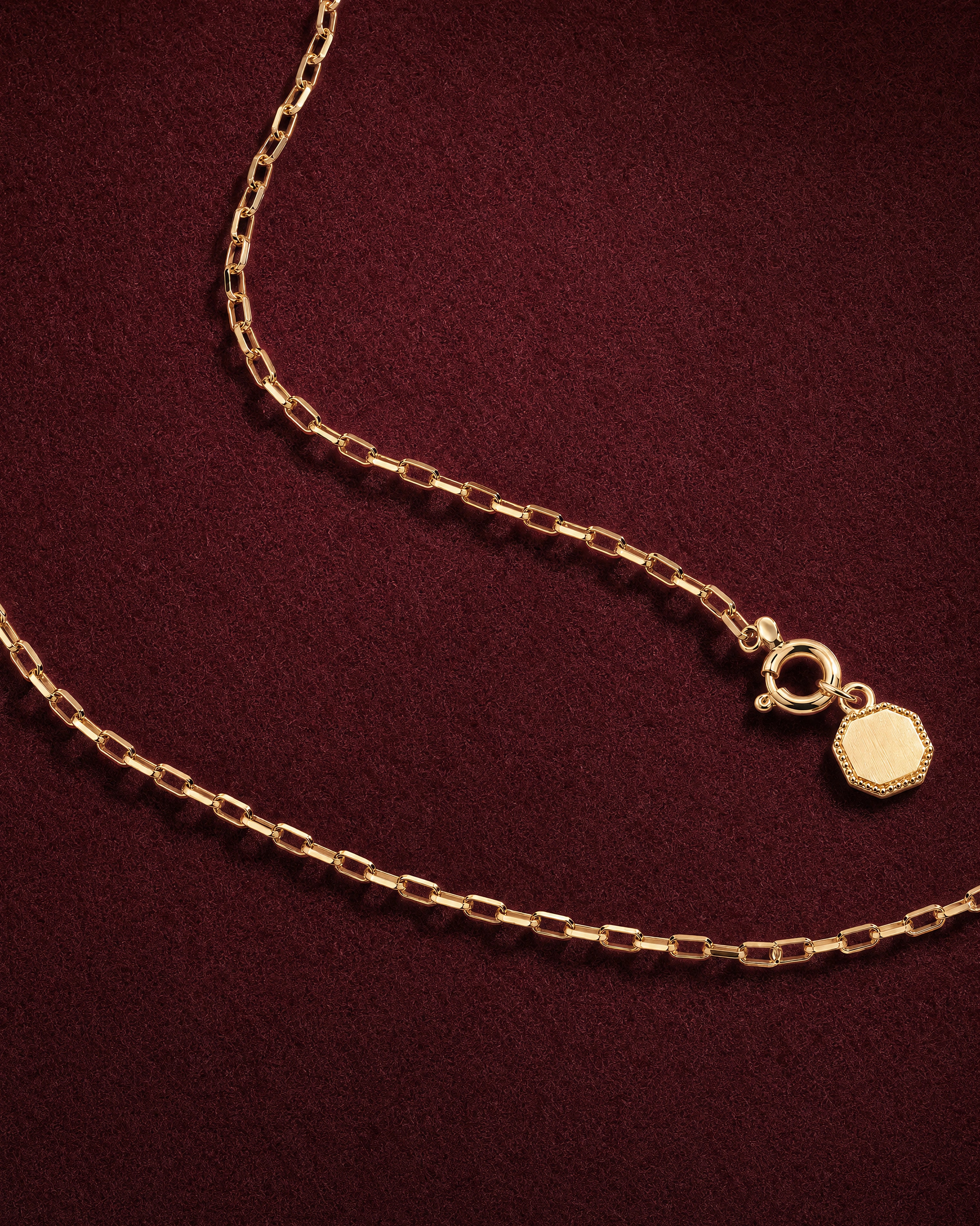 Fil Chain Necklace of octagonal gold links with a small hallmark tag by the clasp, on garnet jeweler's felt