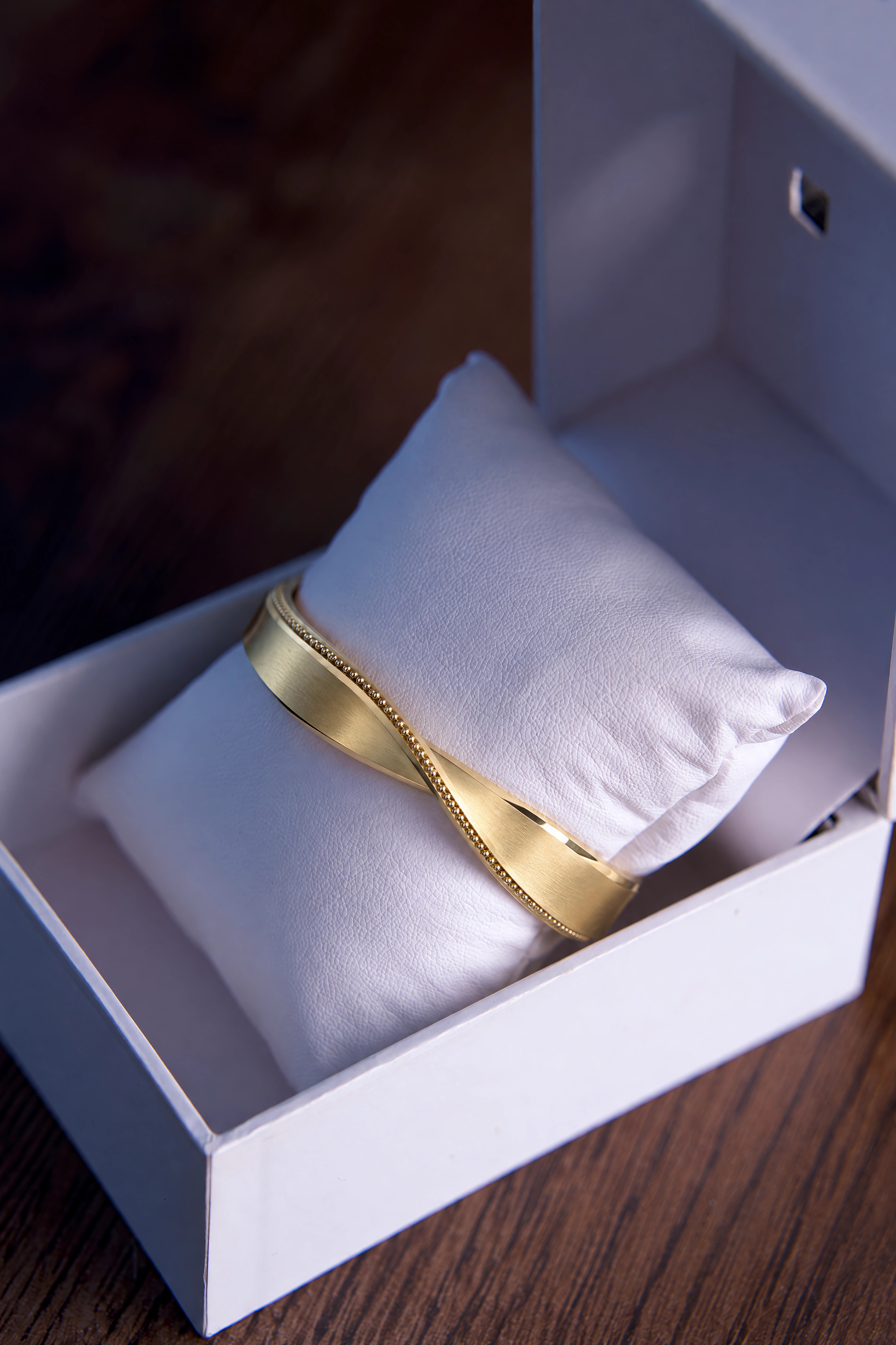 A finished VÉRA cuff on a pillow inside an open gift box