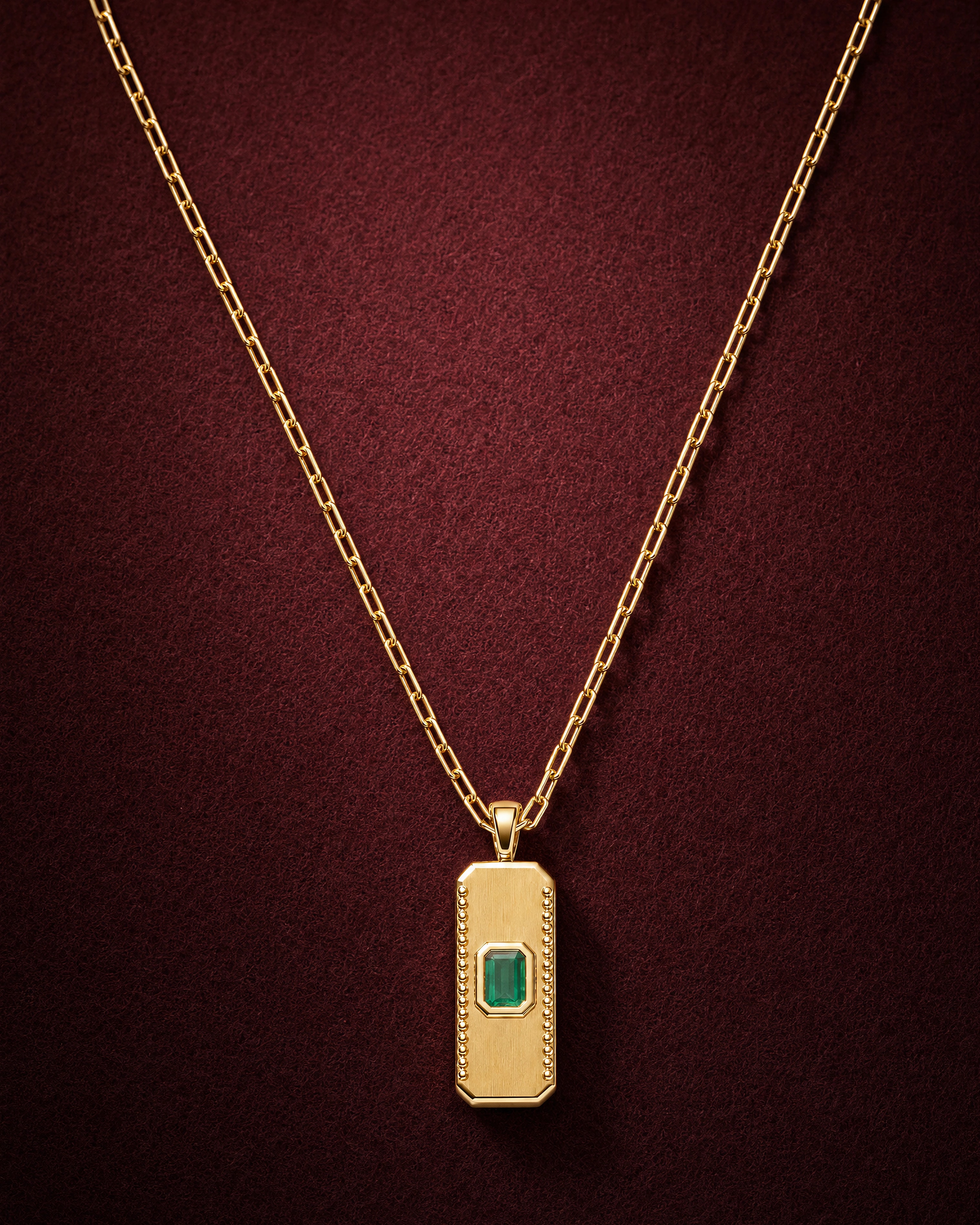 Emerald Bar Pendant in 18k gold with an emerald-cut emerald in an octagonal bezel, on garnet jeweler's felt