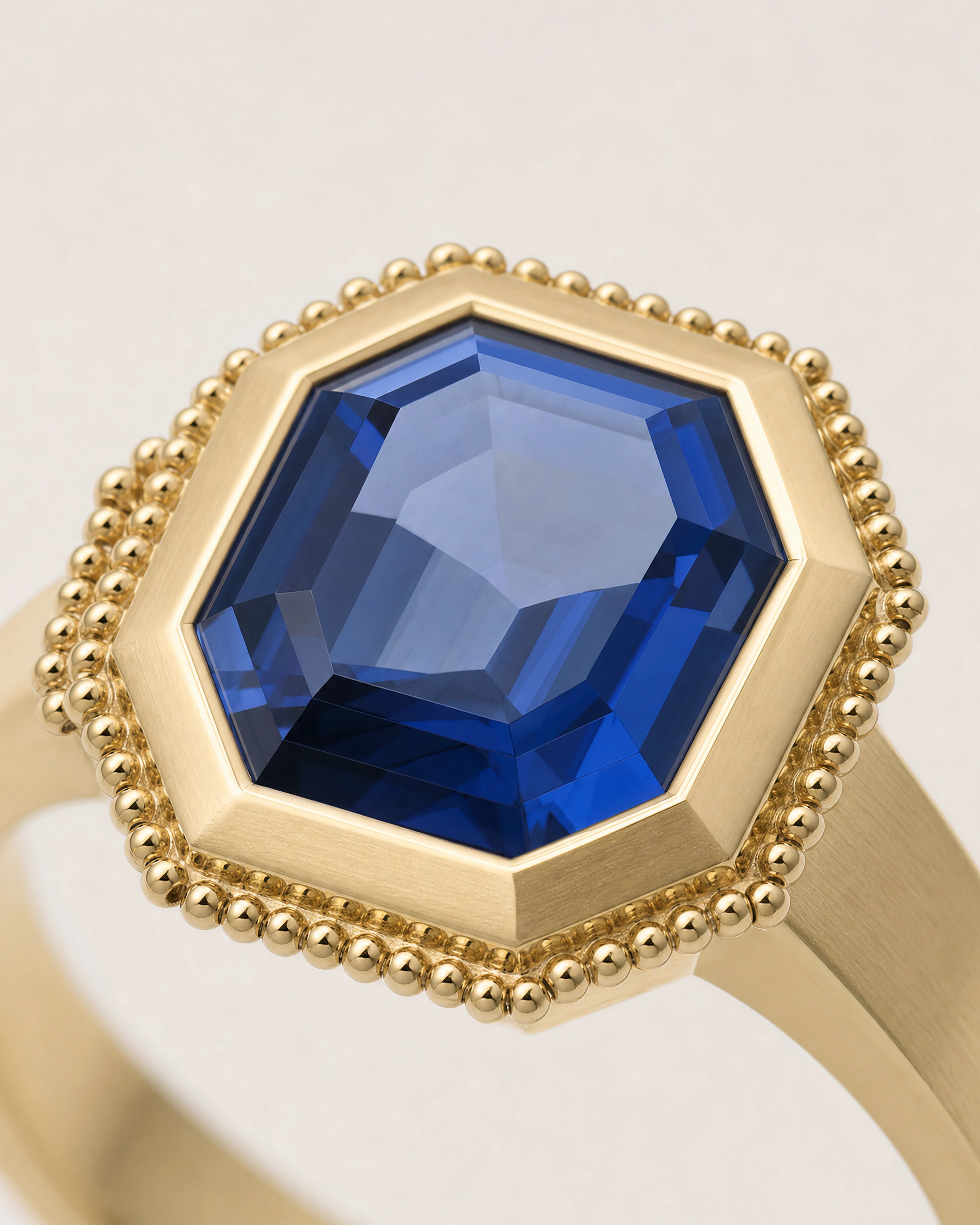 A step-cut sapphire in a chamfered gold bezel ringed with granules