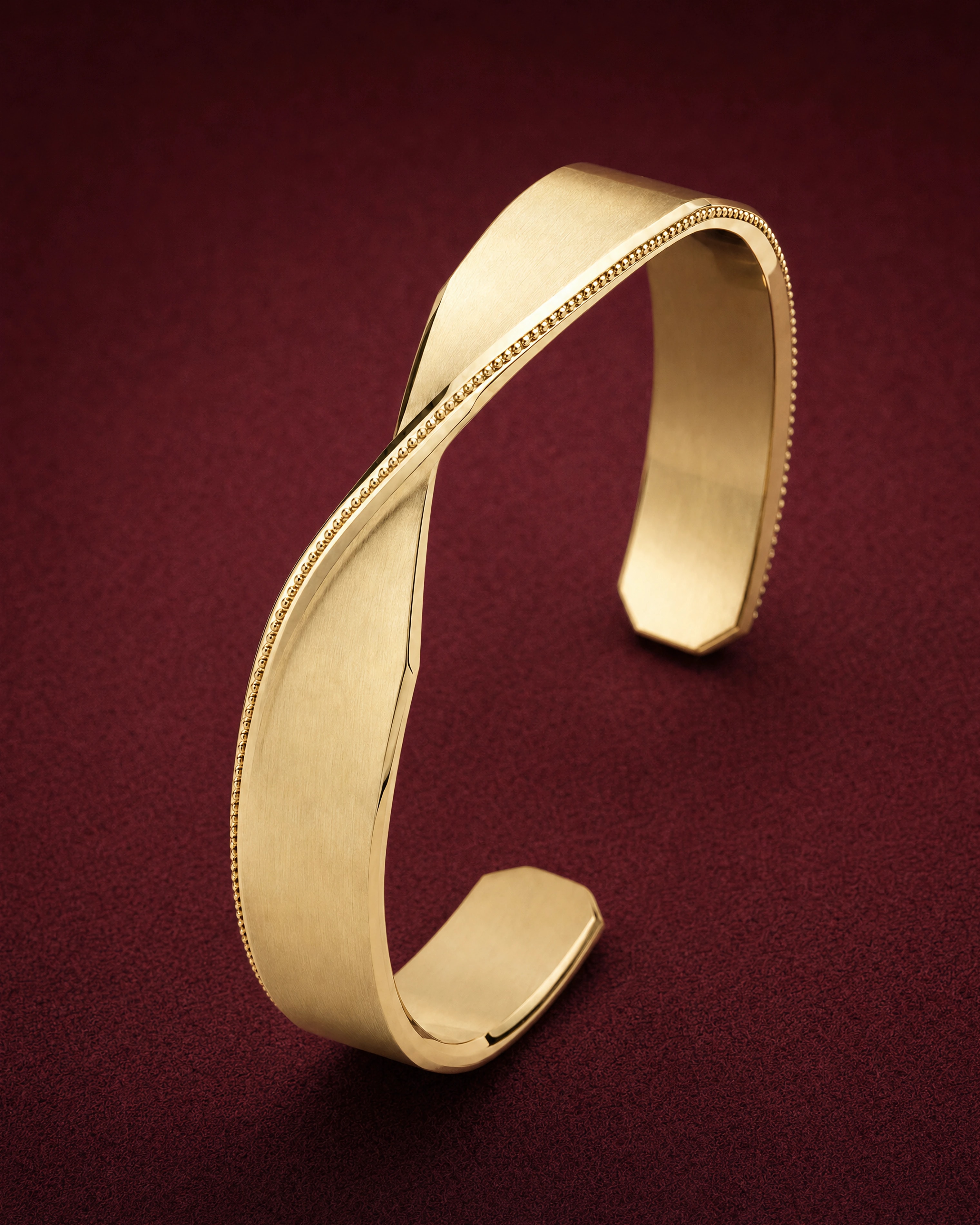 Ribbon Cuff in 18k gold, a satin band with chamfered edges twisted once, on garnet jeweler's felt